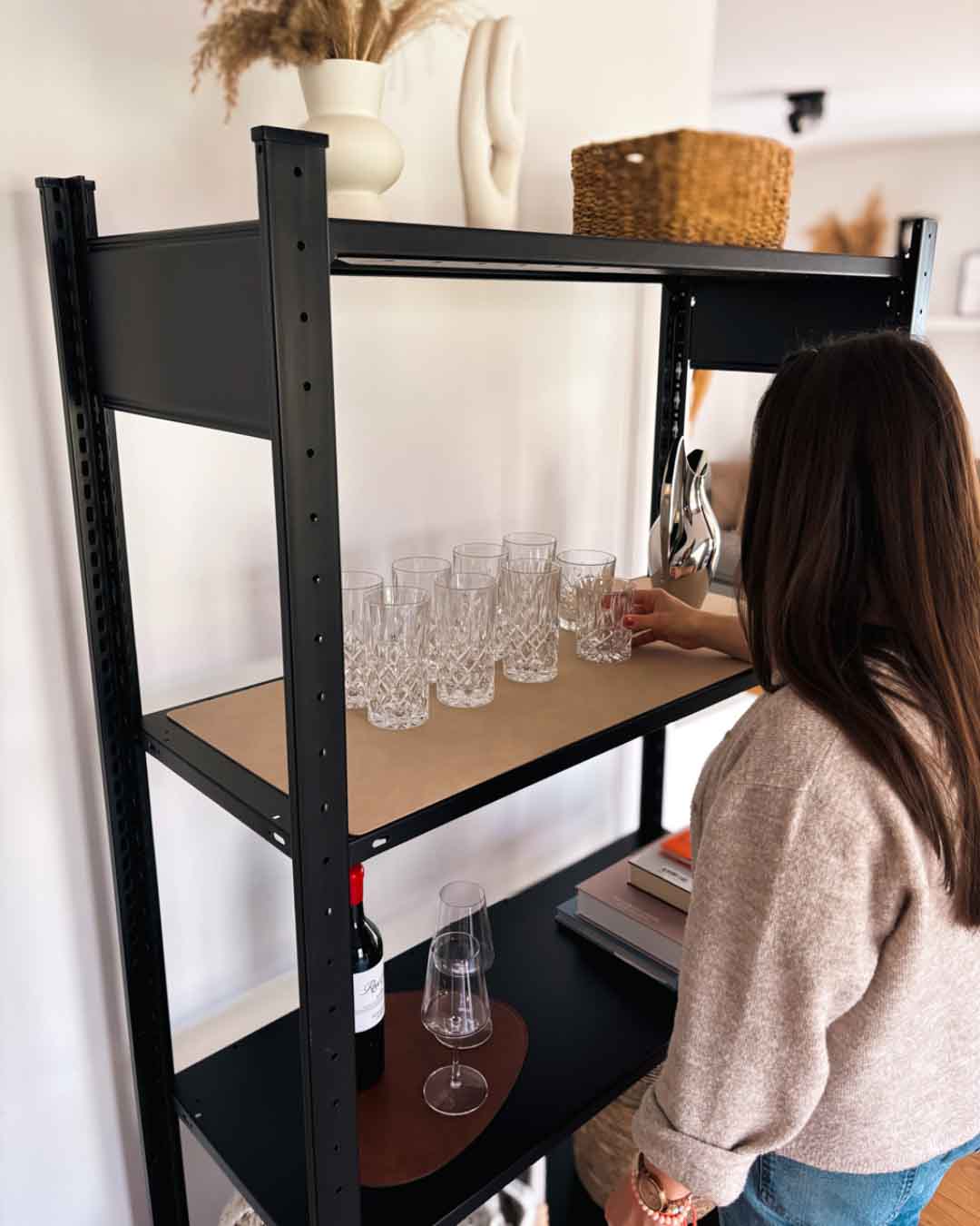 ENZO Design-Unterlage aus recyceltem Leder auf einem schwarzen Regal im Wohnraum mit Person und Gläsern