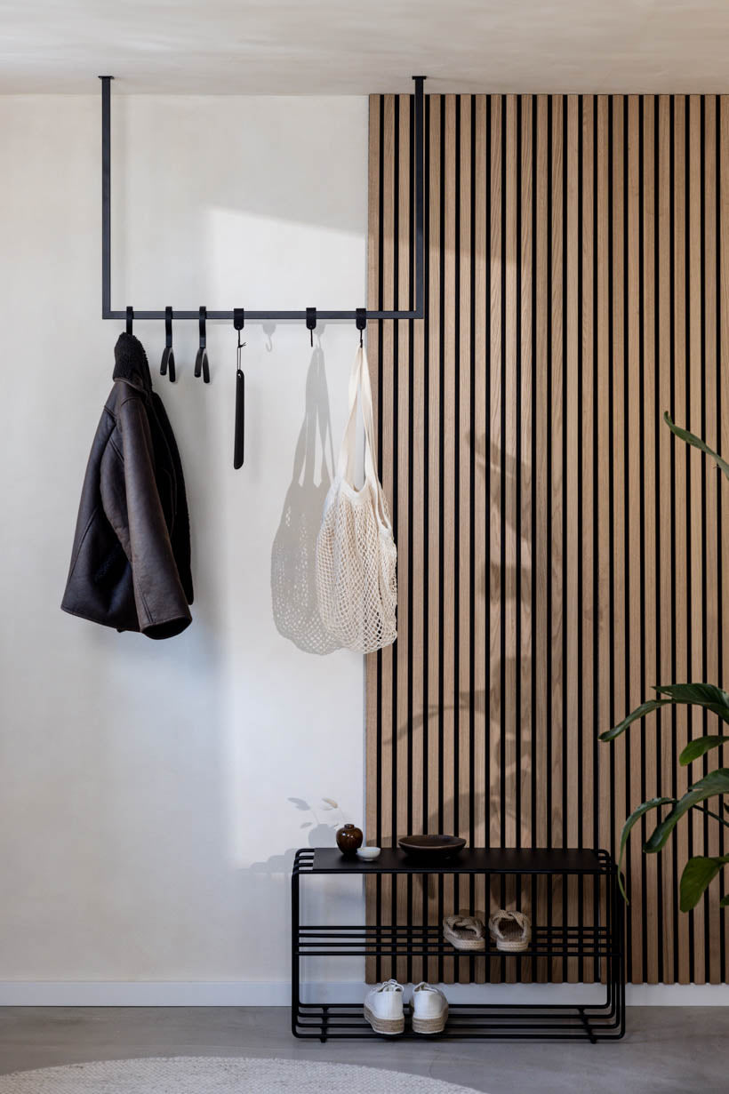 RUBI Kleidergarderobe aus schwarzem Stahl mit Hakenleiste und Schuhbank im modernen Flur mit Holzlamellenwand