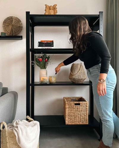Schwarzes DONIA Design Standregal aus Stahl mit 150 cm Höhe im Wohnraum mit Person in Anwendung