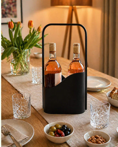 Schwarzer LUNO Flaschenträger aus Stahl mit zwei Weinflaschen auf modern gedecktem Esstisch mit Gläsern, Snacks, Tulpen und warmer Beleuchtung.